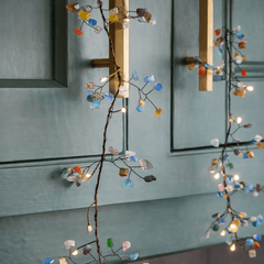Colourful gem fairy lights with warm white LEDs draped across a decorative indoor display.