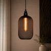 Decorative pendant light with mesh design hanging against a neutral wall.