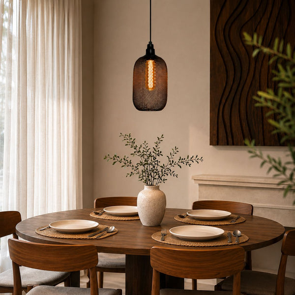 Dining room with a wooden table set for four, a vase with plants, and a hanging light fixture.