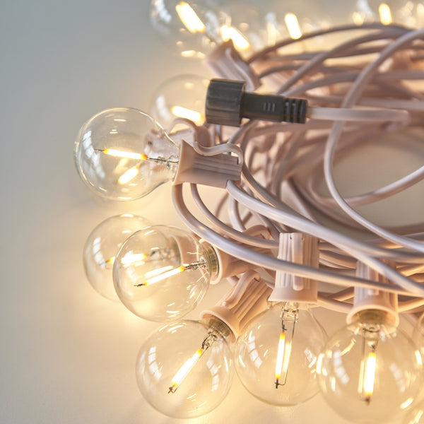 Pink festoon light string featuring clear globe LED bulbs with visible filaments.
