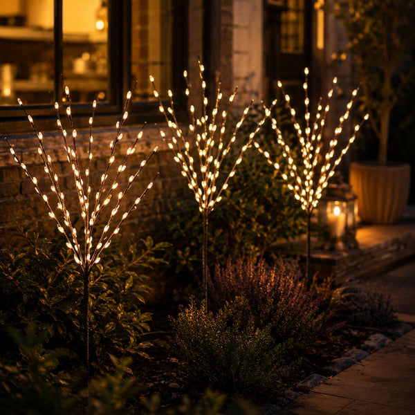 Decorative outdoor lights shaped like branches in a garden setting at night.