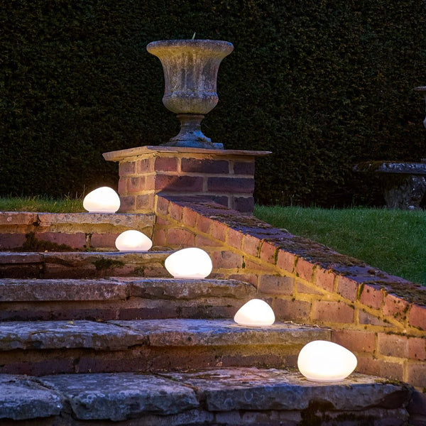 Ambient outdoor stone-shaped LED path lights illuminating stone garden steps at night.